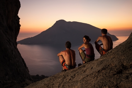 Three rock climbers wearing safety harness having rest at sunset  With picturesque view of Telendos Island in front  Kalymnos Island, Greece の写真素材