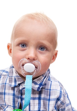 Closeup of cute blonde blue-eyed little boy with a pacifier over white backgroundの写真素材