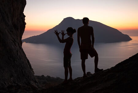 Silhouettes of two young people having fun at sunset, Kalymnos island, Greeceの写真素材