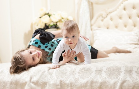 Young Caucasian mother and baby son on bed at homeの写真素材