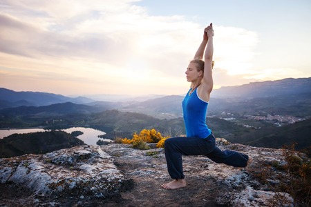 Young Caucasian woman working out on a rock against valley viewの写真素材