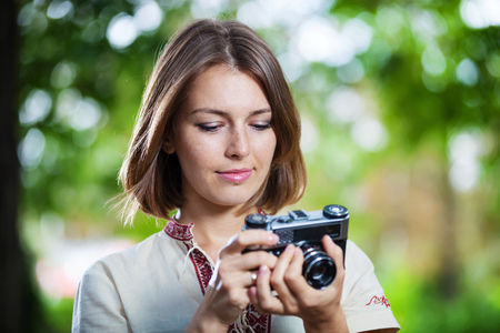 Young woman looking at screen of retro style camera and smilingの写真素材