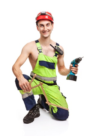 Young handsome contractor holding ruler and electric screwdriver. Isolated over white background.の写真素材