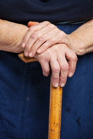 Closeup of senior woman\'s hands on wooden walking stickの写真素材