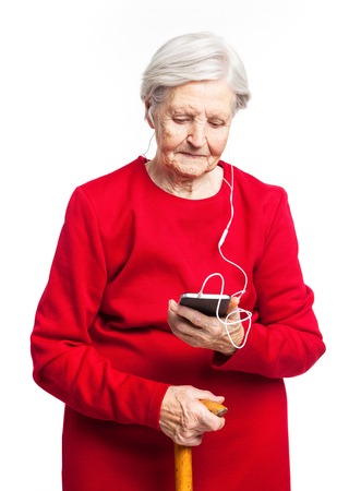 Senior woman listening to music over white backgroundの写真素材