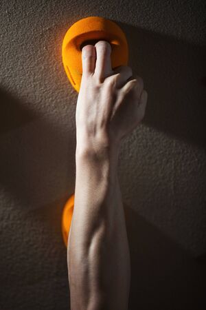 Cropped view of rock climber gripping handhold with two fingersの写真素材