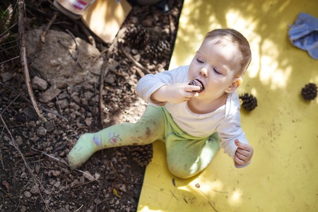 Little boy biting cone while sitting on touristic mat on groundの写真素材
