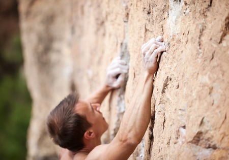 Cropped view of male rock climber on cliff, hands in focusの写真素材