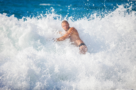 Young man bathing in storming sea, high wave just washed his over, water in focusの写真素材