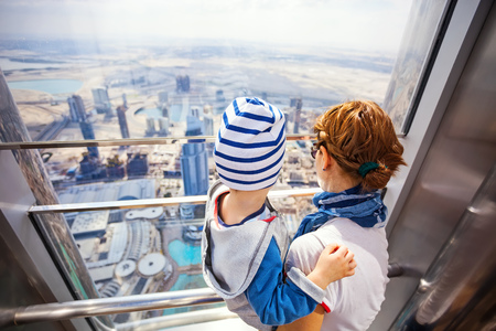 DUBAI, UAE - FEBRUARY 24: Young woman and her toddler son looking out of the window, while visiting At The Top - Observation Deck of Burj Khalifa. Picture taken on February 24, 2015.のeditorial素材