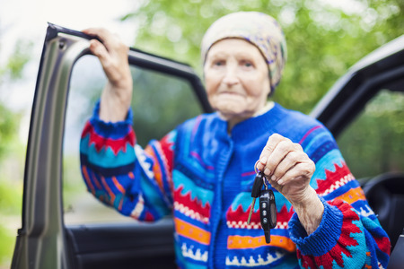 Senior woman holding car key and smiling, selective focusの写真素材