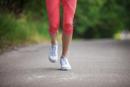 Cropped view of woman athlete running on pathway in parkの写真素材