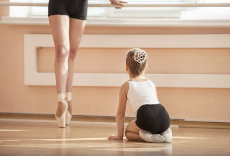 Girl beginner watching classmate standing en pointe in ballet dancing classの写真素材
