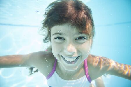 Joyful girl swimming underwater in poolの写真素材