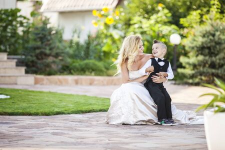 Happy bride and smiling little boy outdoorsの写真素材
