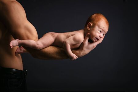Young Caucasian man holding holding little son over black backgroundの写真素材