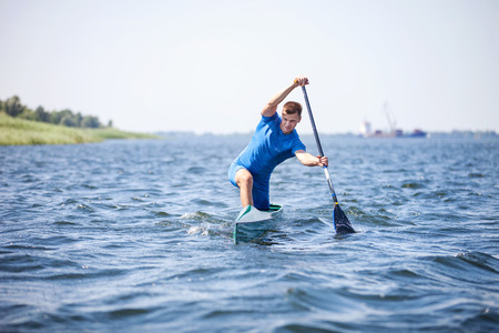 Young man rowing in canoe along a river