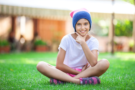 Cheerful young girl sitting on the grassの写真素材