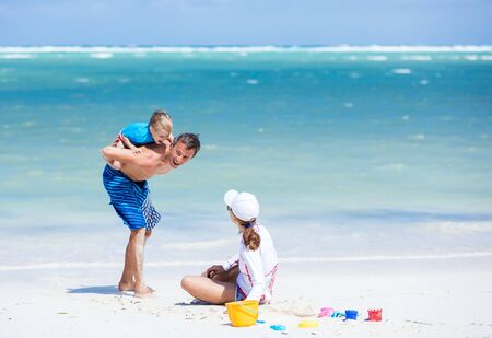 Caucasian couple with little son having fun on the beachの写真素材