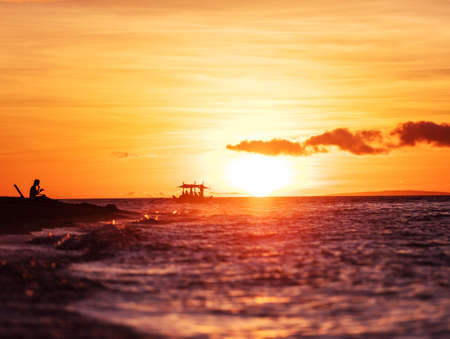 Young woman watching sunset while sitting on the beach