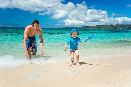 Father and son having fun on a tropical beachの写真素材