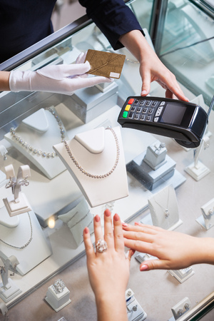 Young woman buying a golden ring and paying with a credit cardの写真素材