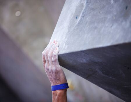 Closeup of man's hand on handhold on artificial climbing wall, hand in focusの写真素材