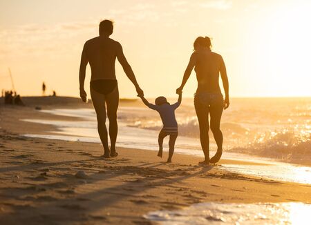 Happy family with little boy together at sunsetの写真素材
