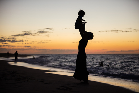 Mother and son having fun on the beach at sunsetの写真素材