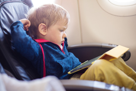 Little boy using tablet on board of aircraftの写真素材