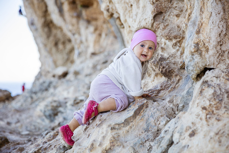 Little girl playing on rocks near climbing sector, blurred viewの写真素材