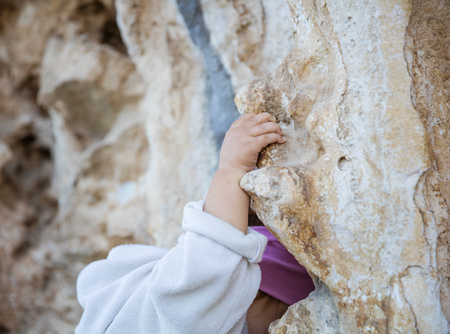 Closeup of little girl gripping cliff in climbing sector, hand in focusの写真素材