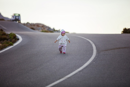 Cute little girl walking down road. Parents' car parked along road in distance.の素材 [FY31071559229]