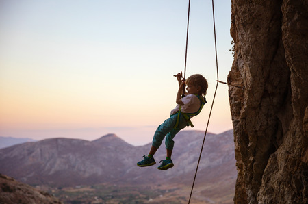 Little boy rock climber being lowered downの写真素材