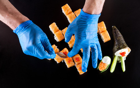 Cropped view of chef preparing sushi over black background