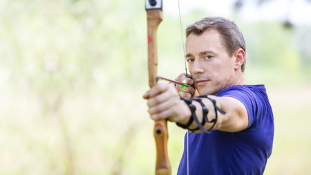 Bowman aiming arrow at target, image with selective focus