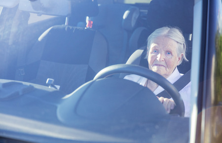 Gray-haired senior woman driving car