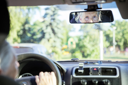 Reflection of senior woman in rear view mirror, aged lady driving carの写真素材