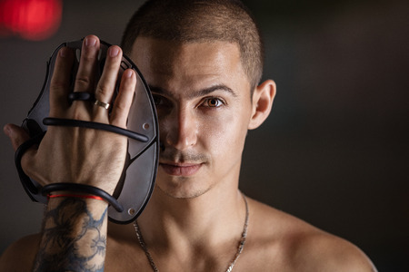 Handsome young man posing with swim paddle in indoor swimming poolの写真素材