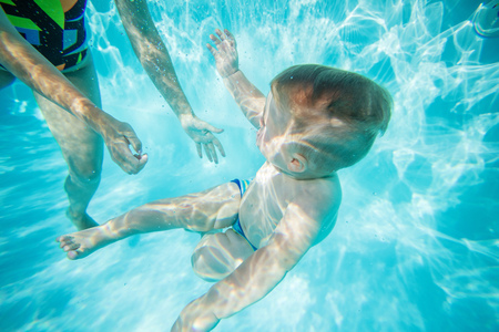 Mother or instructor teaching little boy to swim underwater in poolの写真素材