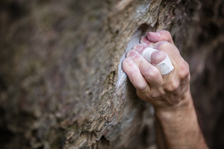 Closeup view of rock climber's hand gripping hold on natural cliffの写真素材