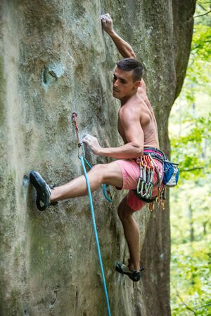 Young male rock climber on challenging route, gripping small handholdsの写真素材