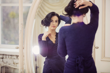 Portrait of beautiful young woman looking in mirrorの写真素材