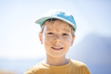 Cute young boy with with dirty smudges on face after playing outdoors