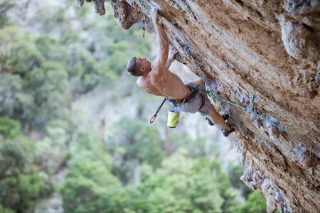 Young male rock climber on challenging route on overhanging cliffの写真素材