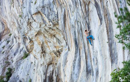 Caucasian young man climbing challenging route on overhanging cliff