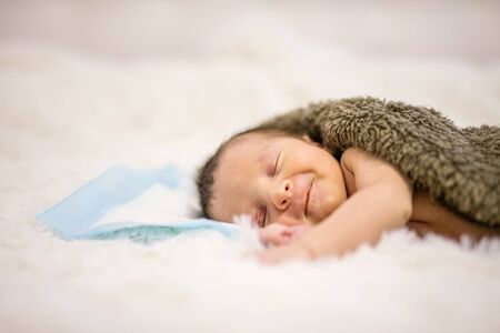 Lovely newborn baby boy sleeping on bed and smilingの写真素材