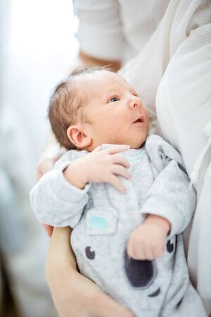 Newborn baby boy in mother's arms. Adorable little baby looking up at mom.の写真素材