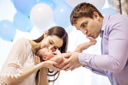 Happy young couple holding and kissing newborn baby boy