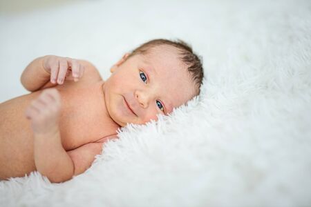 Newborn baby boy lying down on bed and smiling